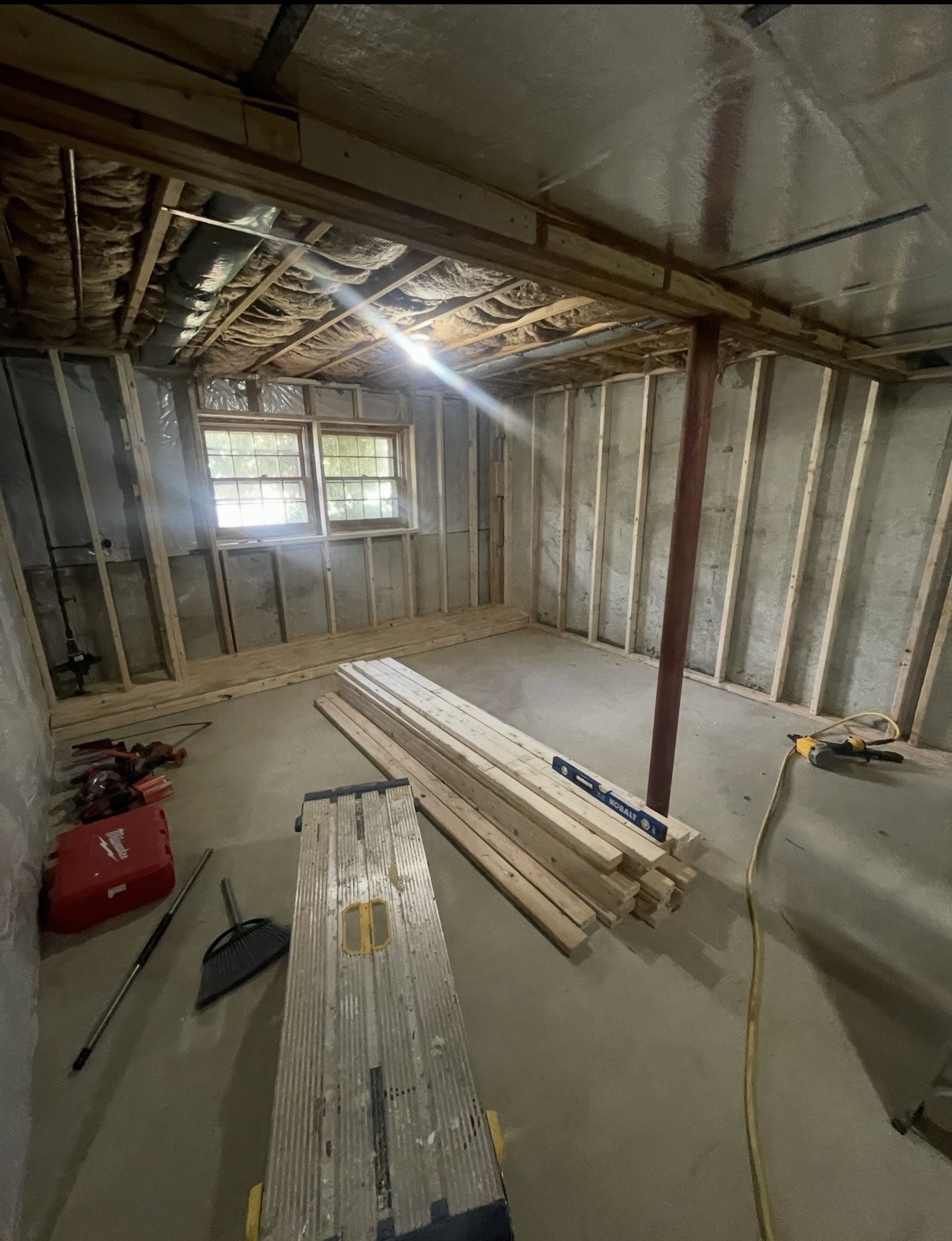 Basement during framing with new pressure-treated lumber, steel lally column, and spray-foam insulation