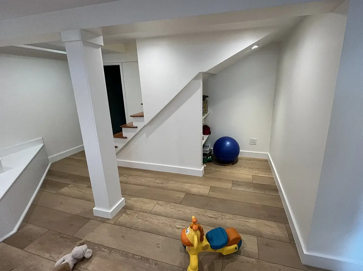 Finished basement playroom with built-in bookshelves and bright white walls