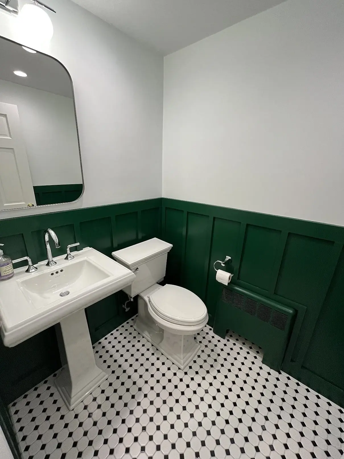 Half bathroom remodel with hunter green board-and-batten wainscoting and black-and-white mosaic tile floor