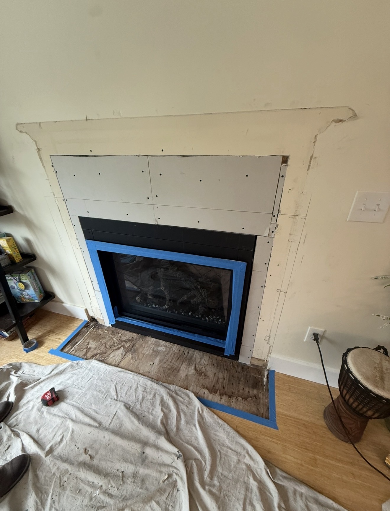 Fireplace surround mid-renovation with new cement board prepped for tile and existing finish removed