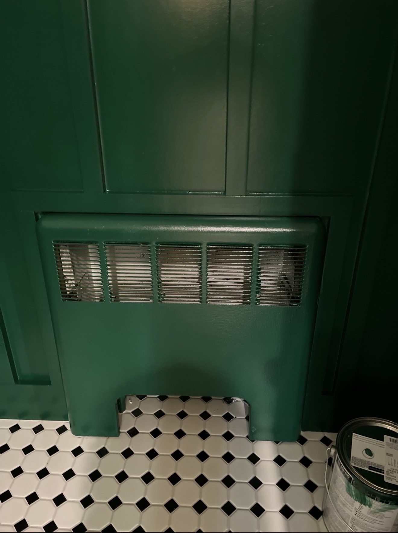Same powder room after — beadboard wainscoting and cast-iron radiator cover finished in deep hunter green over black-and-white octagon tile