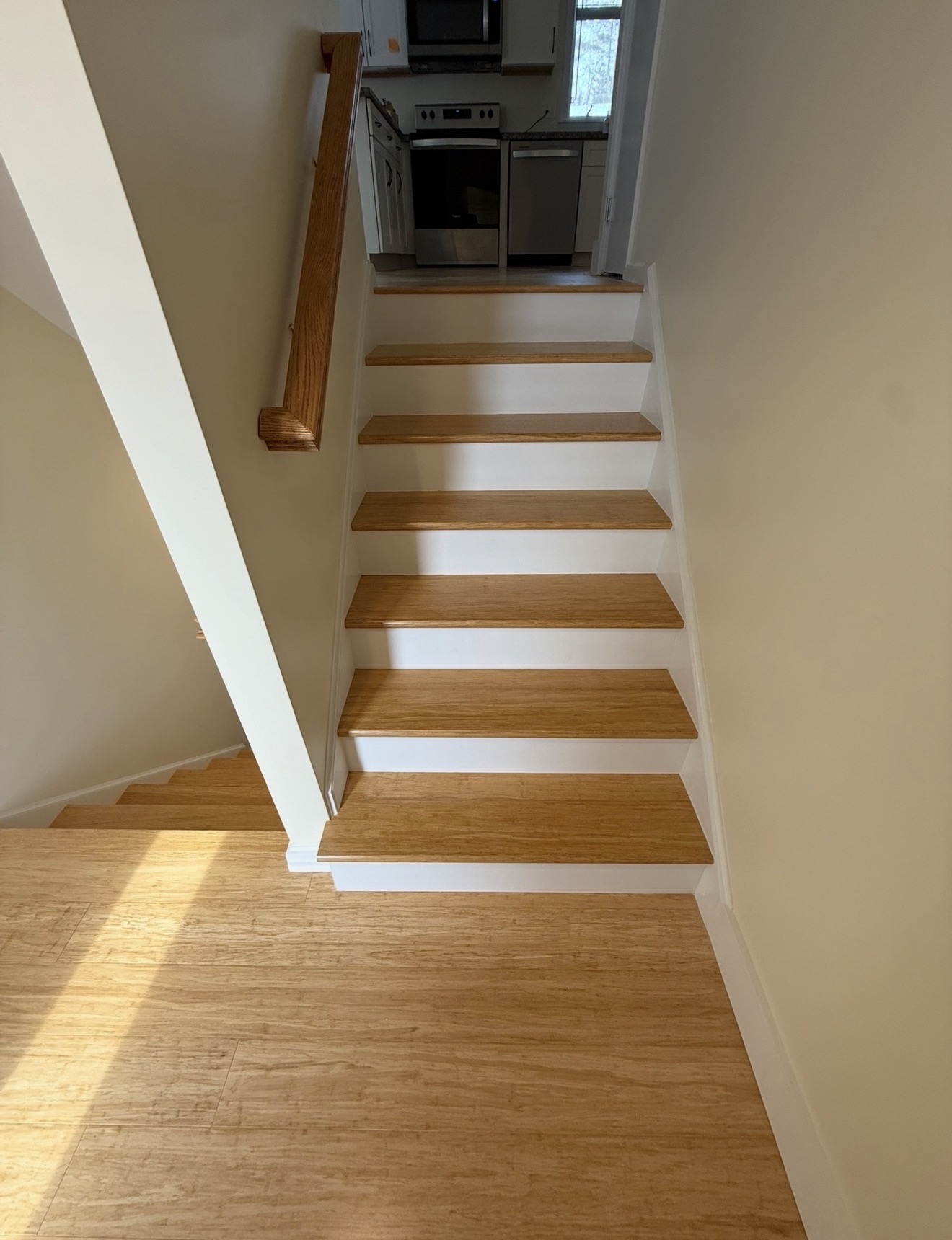 Same staircase after — solid red oak treads with crisp white painted risers and matching oak handrail